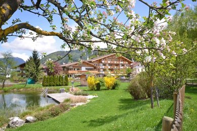 Sommeraufnahme der Liegewiese am Naturpool des Familienhotels Landgut Furtherwirt in Tirol.